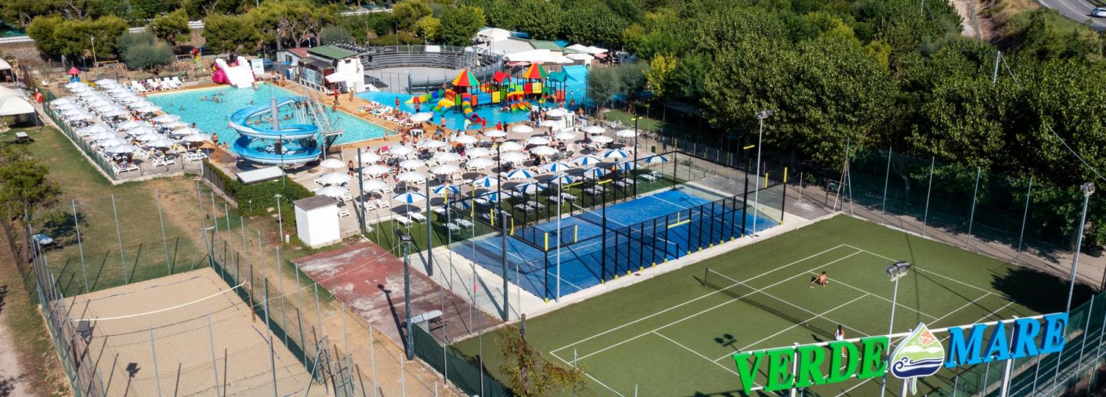 Complexe touristique avec piscines, terrains de sport et vue sur la mer.