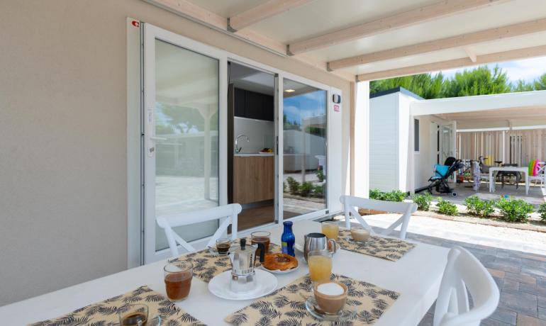 Colazione all'aperto con caffè e succhi, vicino a una veranda moderna.