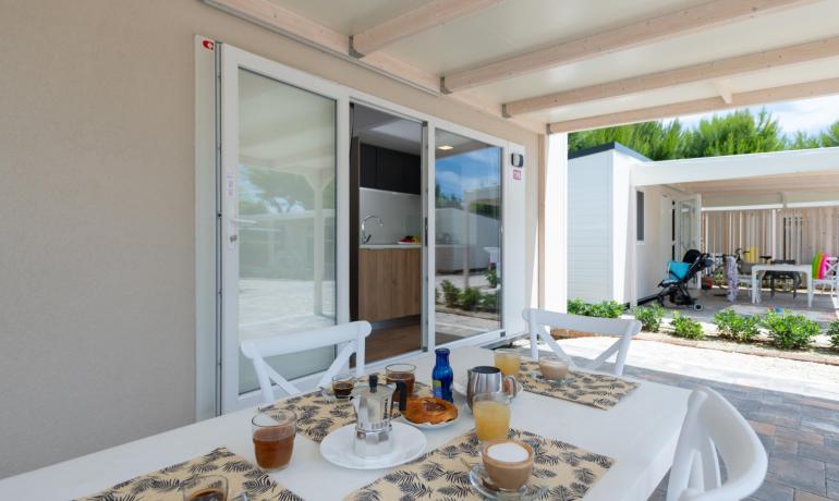 Terrasse avec petit-déjeuner en plein air, vue sur jardin et cuisine moderne.