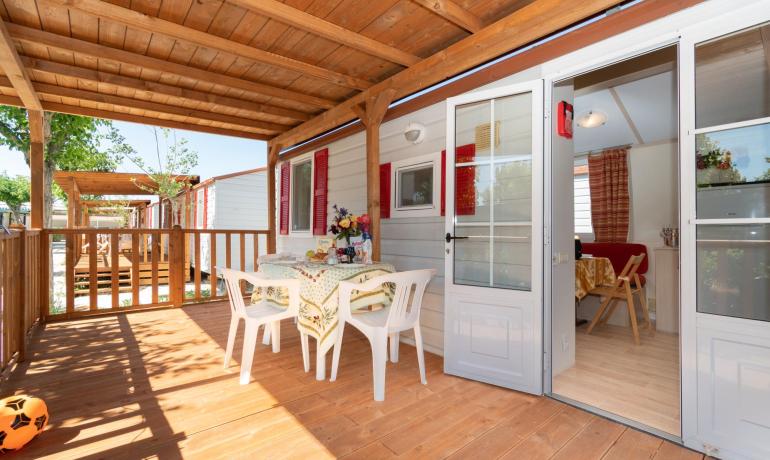 Terrasse en bois avec table dressée et chaises blanches.