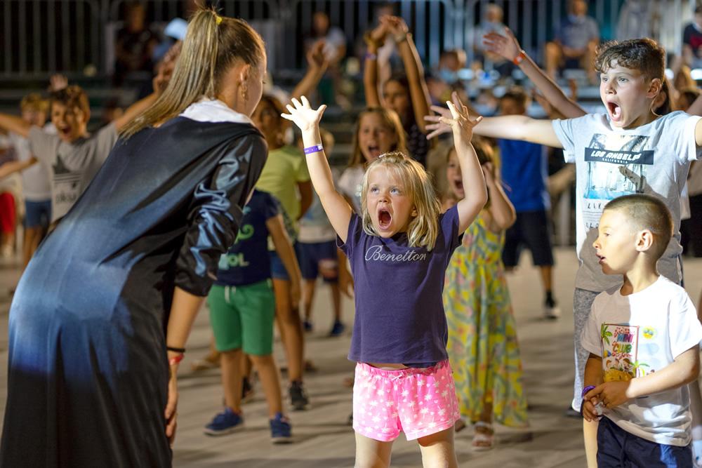 Enfants jouent avec enthousiasme, levant les bras à une fête.