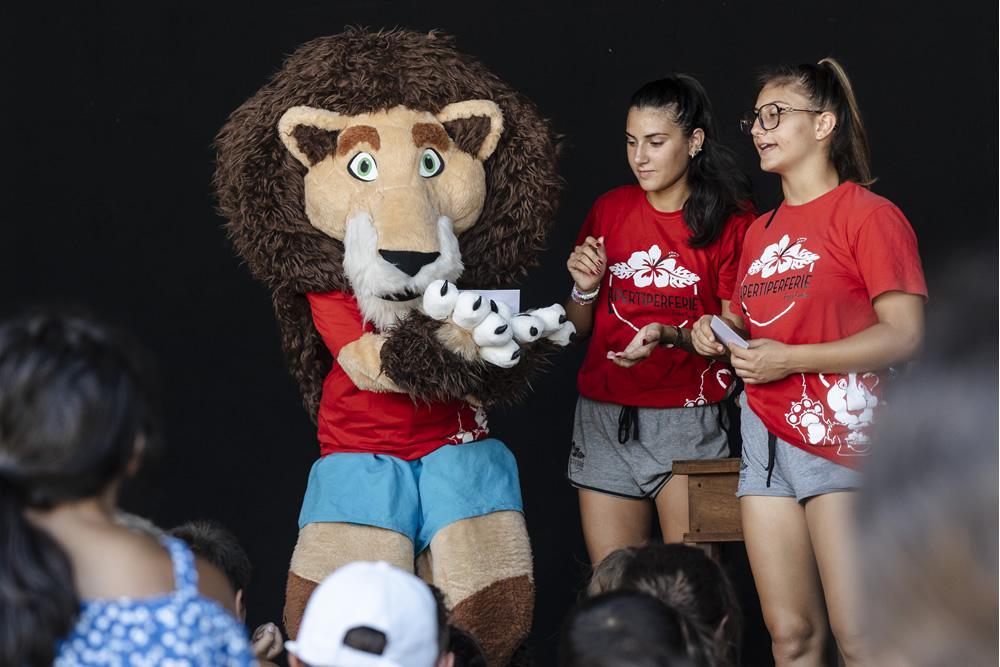 Mascotte lion et deux animatrices interagissent avec des enfants.