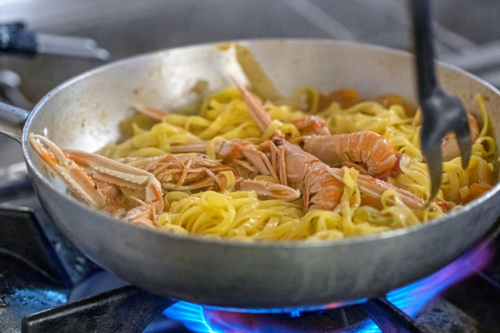 Tagliatelle mit Garnelen in einer Pfanne auf dem Herd.