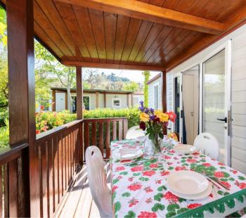 Terrasse avec table dressée, fleurs et chaises blanches.