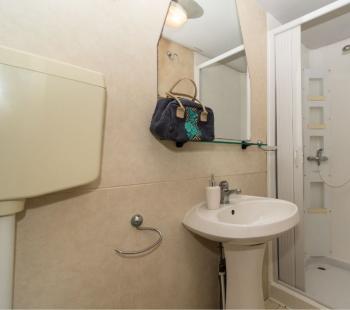 Salle de bain compacte avec douche, lavabo et miroir.