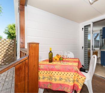 Terrasse avec table dressée, bouteille de vin et fruits.