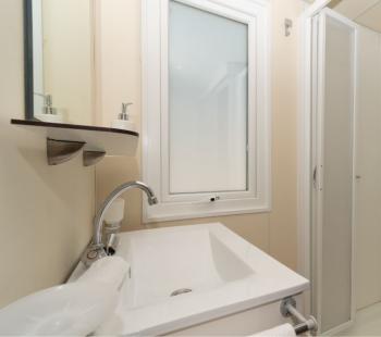 Salle de bain moderne avec douche et lavabo minimaliste.