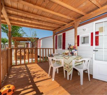 Véranda en bois avec table dressée, vue sur mobil-homes.