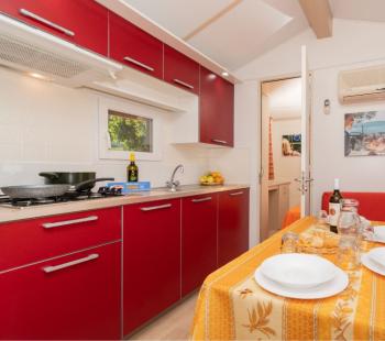 Cuisine moderne avec meubles rouges et table dressée.