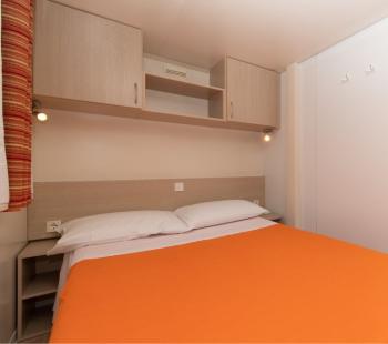 Chambre simple avec couvre-lit orange.