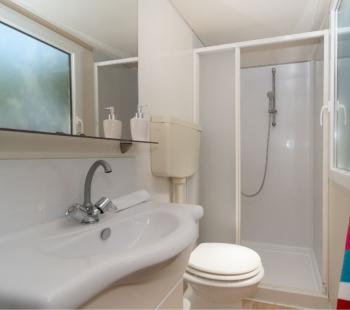 Salle de bain compacte avec douche, lavabo et serviette colorée.