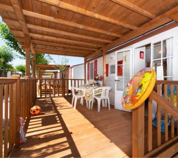 Véranda en bois avec table, chaises et jouets pour enfants.