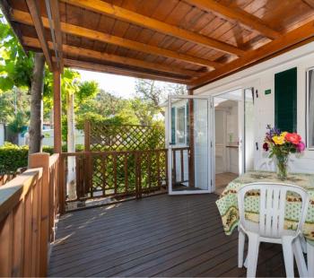 Terrasse avec table, chaises et fleurs, sous un toit en bois.