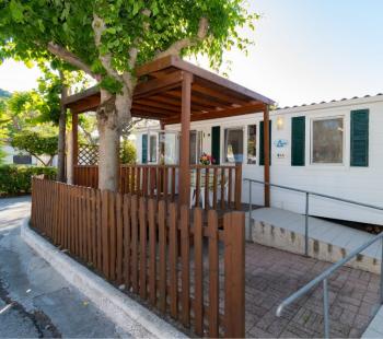 Maison mobile avec terrasse en bois et jardin.