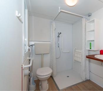 Salle de bain accessible avec douche, lavabo et toilettes.