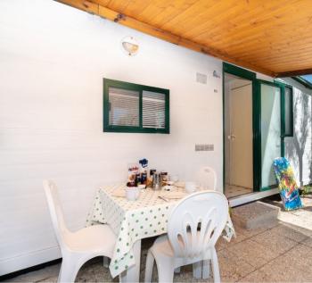 Petite véranda avec table dressée, chaises et skateboard.