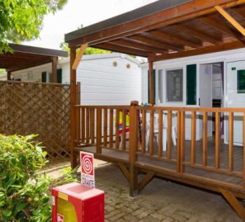 Porche en bois d'une maison mobile au camping, avec des jouets pour enfants.