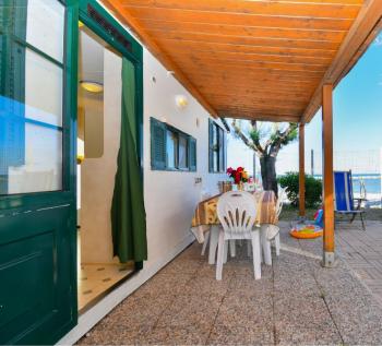 Véranda avec table, chaises et vue sur la mer, ambiance estivale.