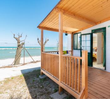 Bungalow en bord de mer avec porche en bois, vue sur la plage.