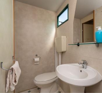 Salle de bain minimaliste avec lavabo, miroir et distributeurs bleus.