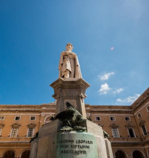 Statue von Giacomo Leopardi auf einem historischen Platz.