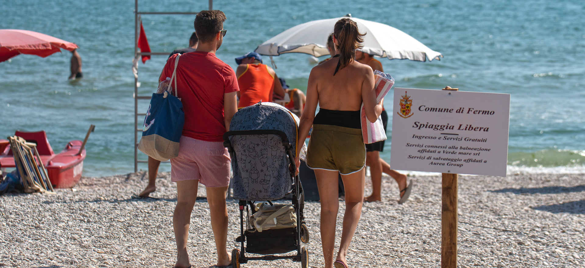 Famille se promène sur la plage avec une poussette.