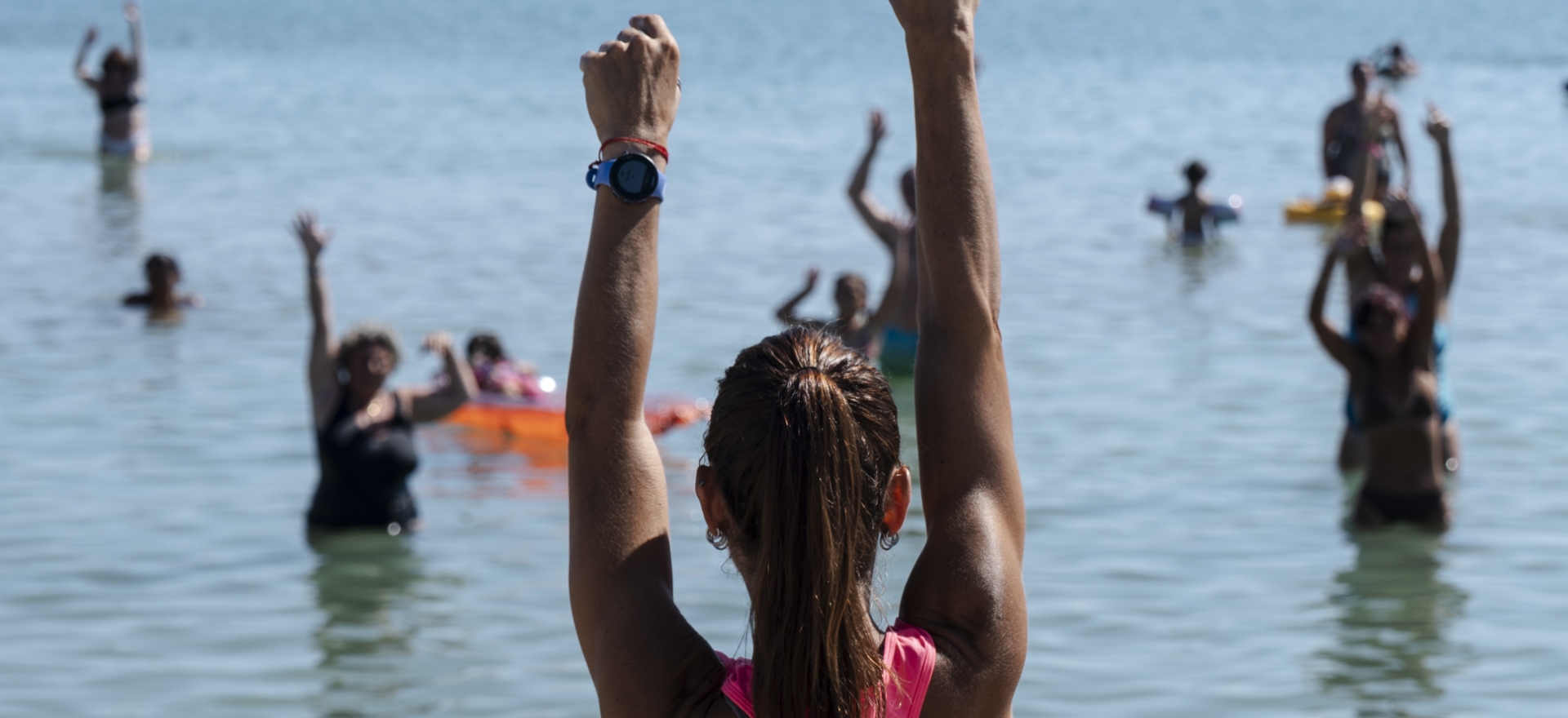 Lezione di aerobica in acqua con istruttore e partecipanti al mare.