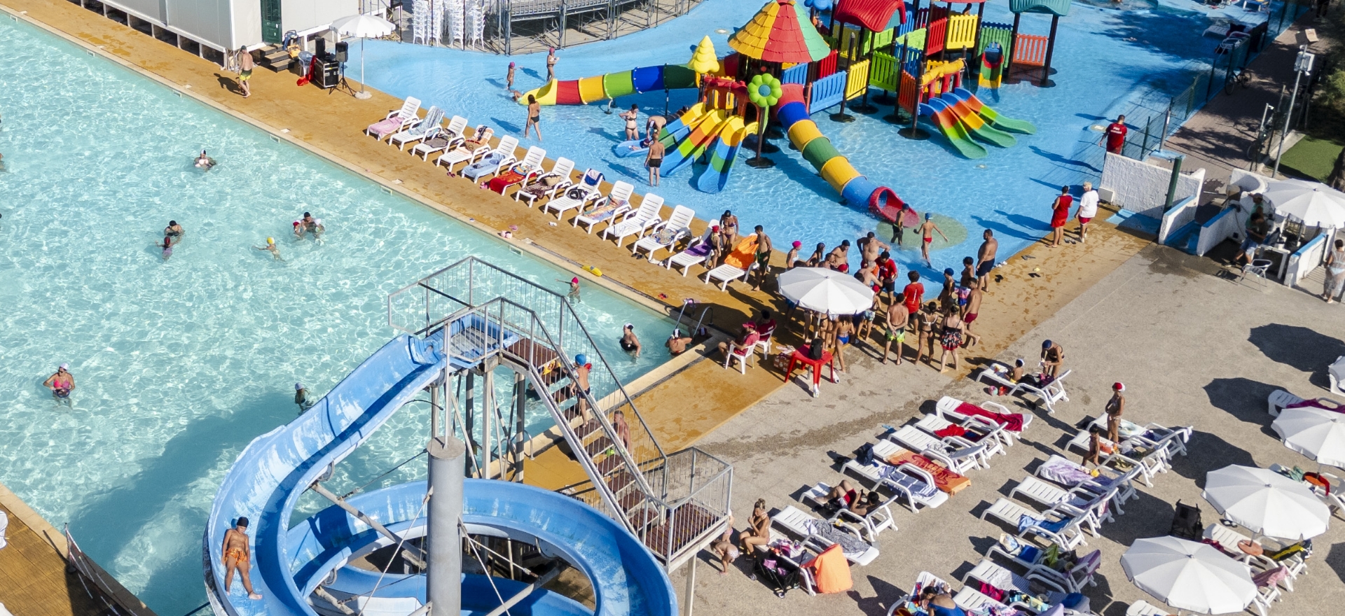 Parco acquatico con piscine, scivoli e area giochi colorata.